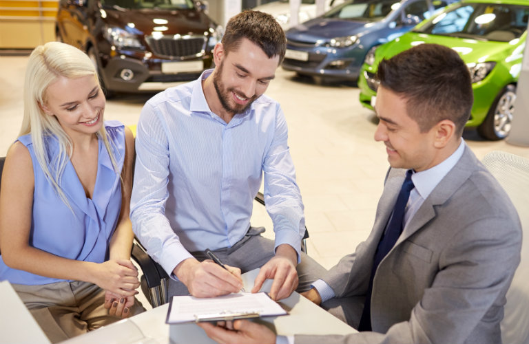 Man-signing-paperwork-at-car-dealership