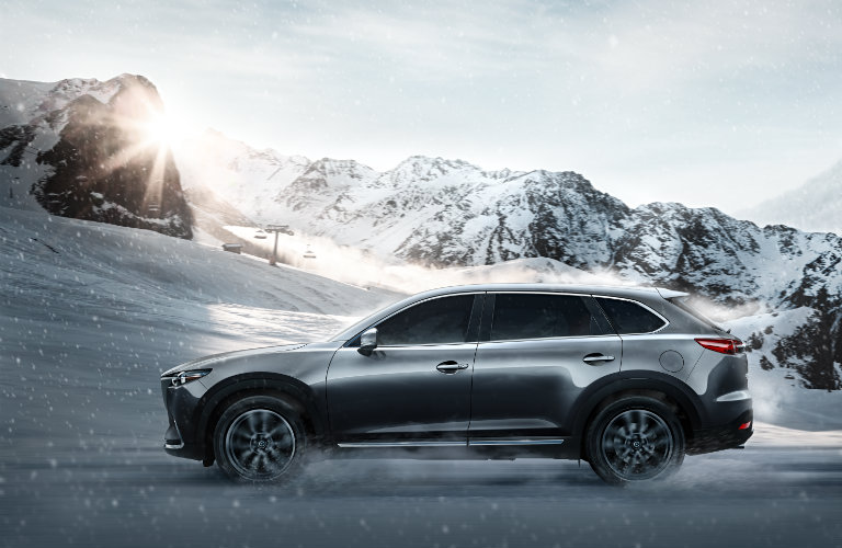 2018-Mazda-CX-9-driving-on-snowy-road-in-front-of-mountains