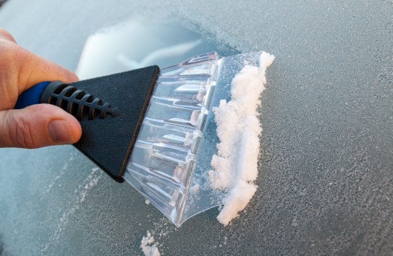 Close-up-of-ice-scraper-scraping-off-windshield