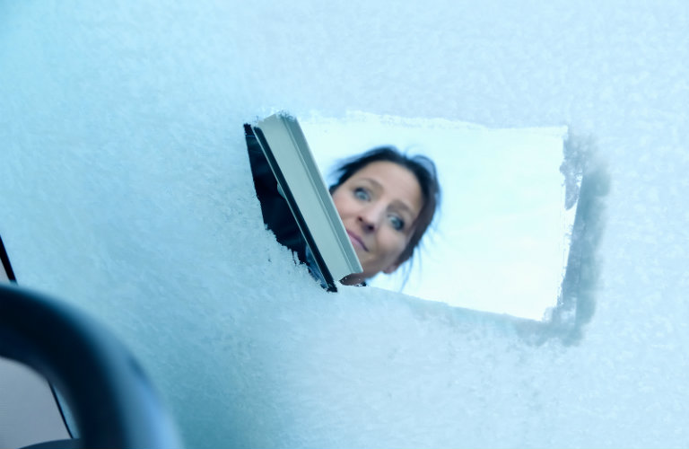 Woman-scraping-off-ice-on-windshield