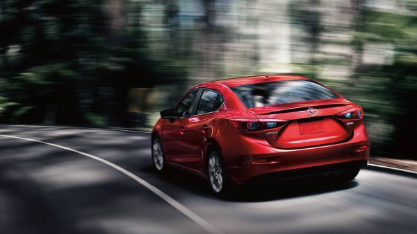 2018 Mazda3 sedan driving on a wooded highway