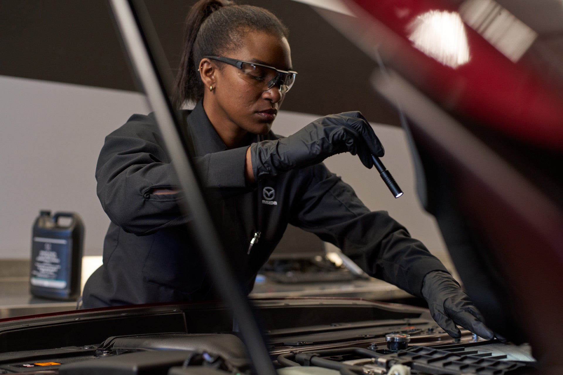 A Mazda technician looking under the hood of a vehicle