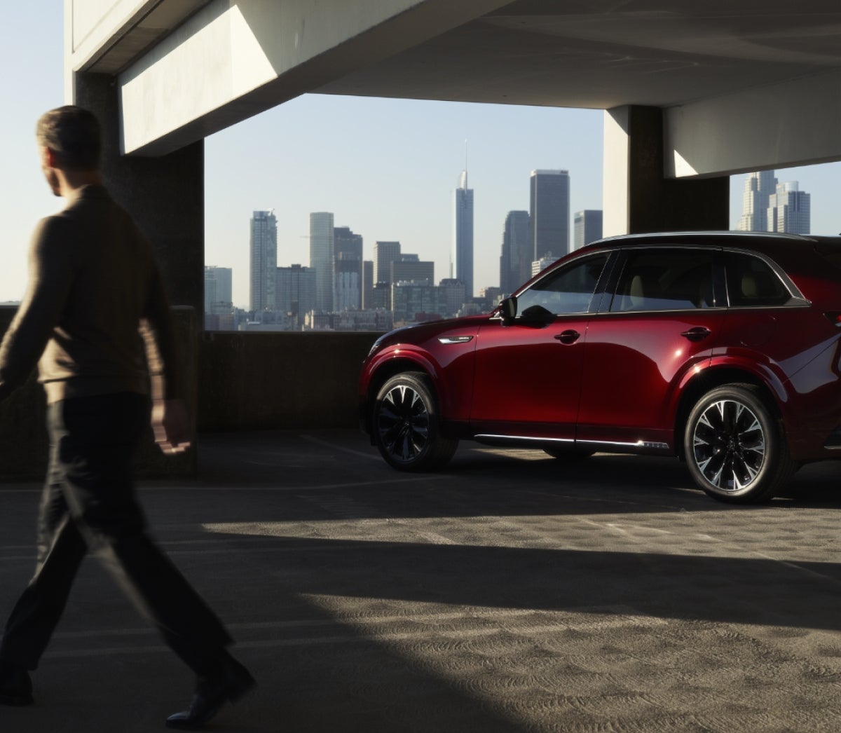 The 2025 Mazda CX-90 in a parking garage with a city skyline in the background
