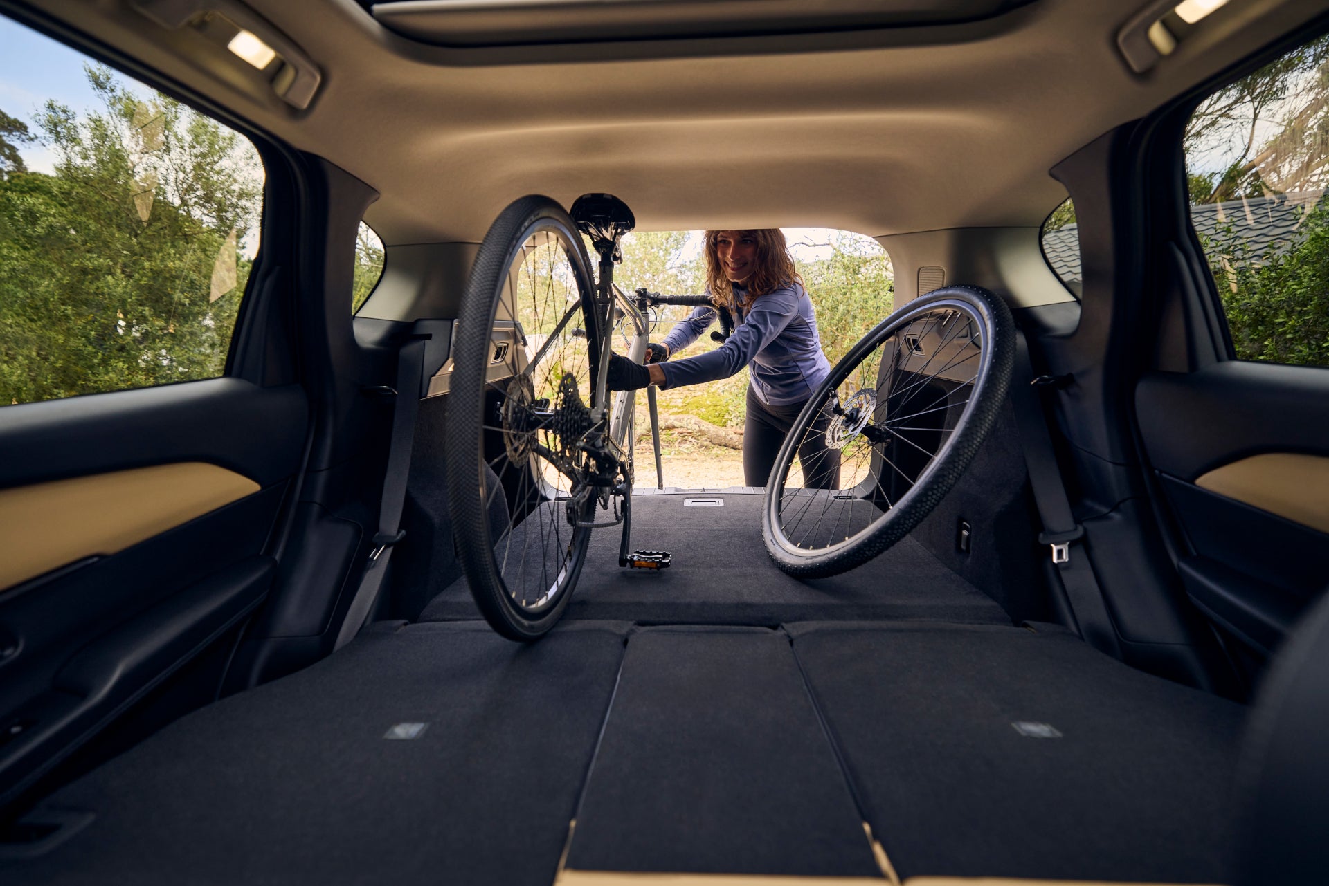 A woman putting a bike in the trunk of the 2026 Mazda CX-5