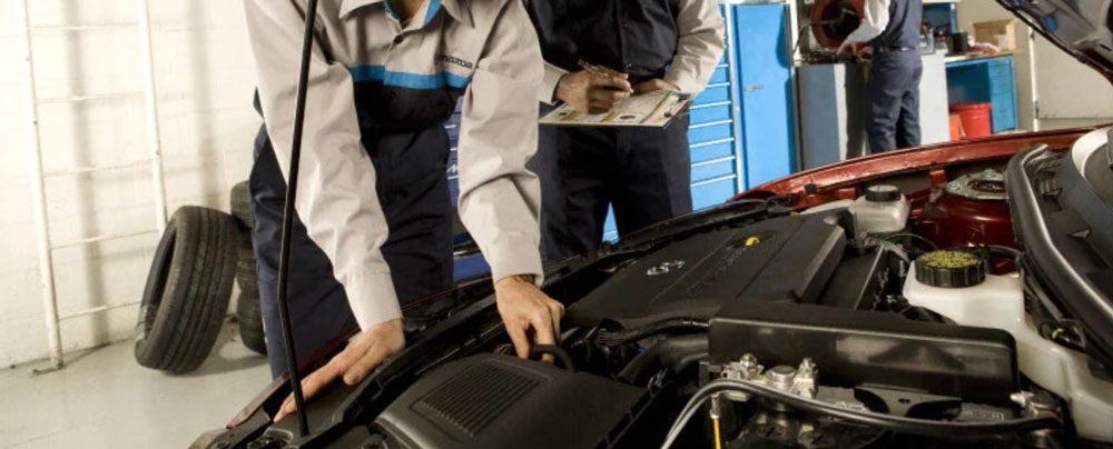 Mechanics performing important service to Mazda car